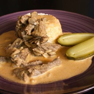 Biff Stroganoff En tallrik med biffstroganoff serverad med saltgurka och ris – klassisk och krämig rätt med smakrik sås