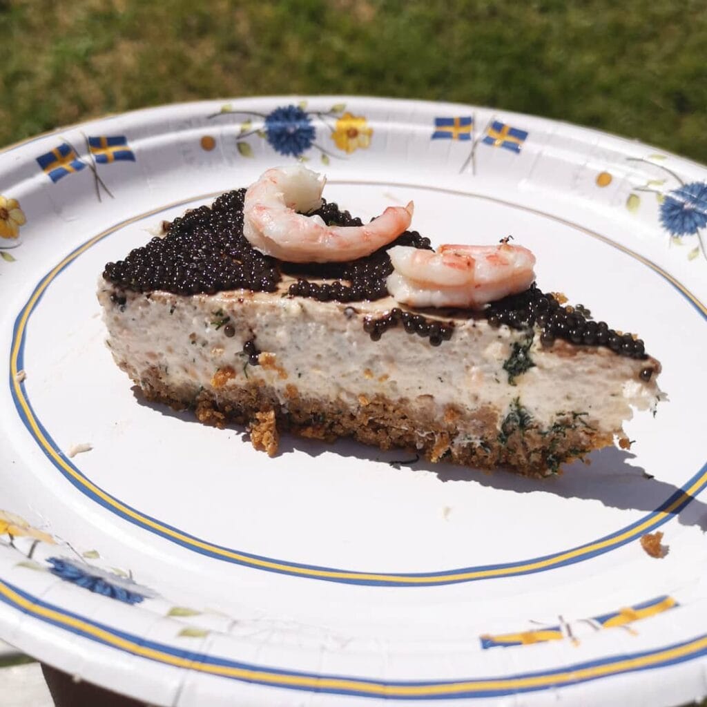 En bit kallrökt laxtårta med lager av krämig fyllning, dekorerad med dill och citron