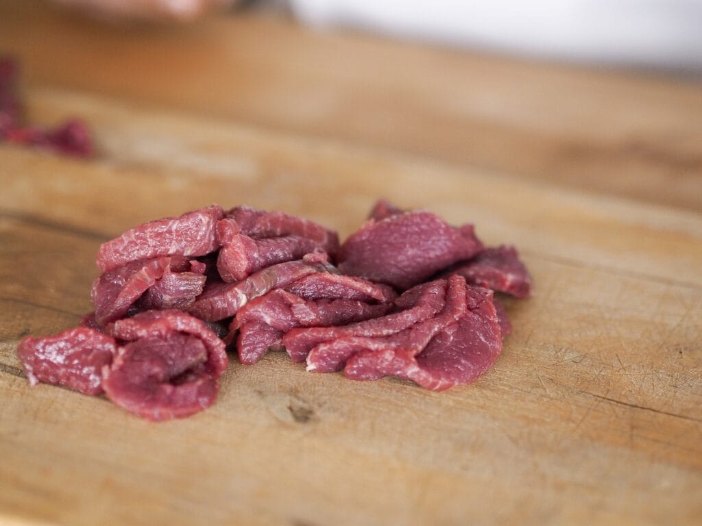 En hög med strimlat rått kött Biff Stroganoff redo till stekpannan