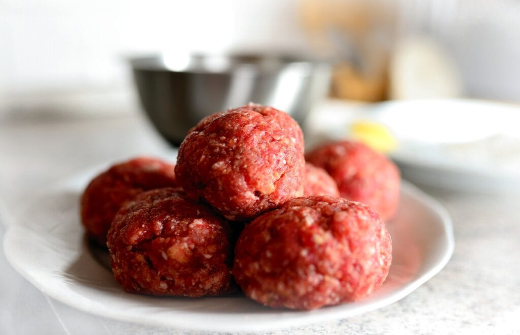 Rullade råa köttbullar liggande på varandra 
