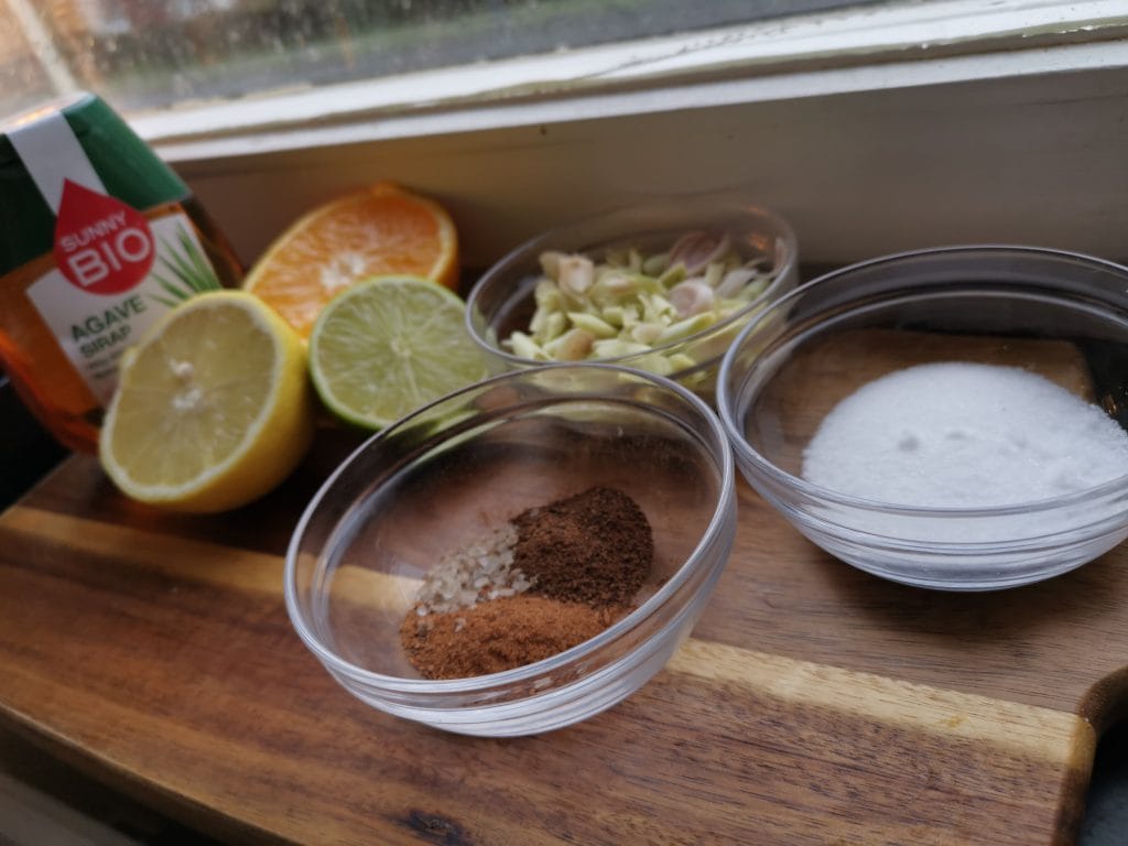 Skärbräda med ingredienser för att göra egen hemmagjord tonic. Kinabark, citrongräs, apelsin, citron och lime.