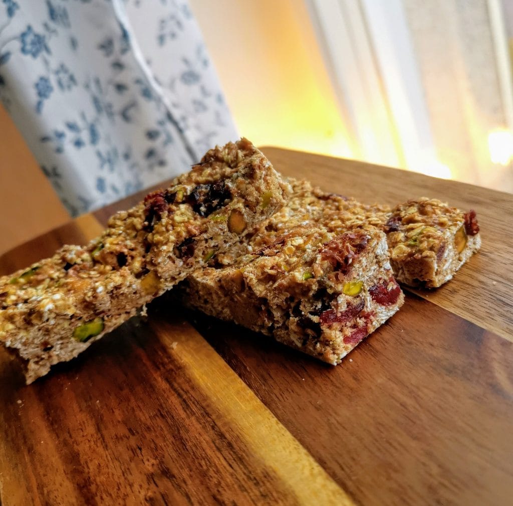 Hemmagjorda proteinbars på skärbräda med varma färger. Nötter frukt och havregryn