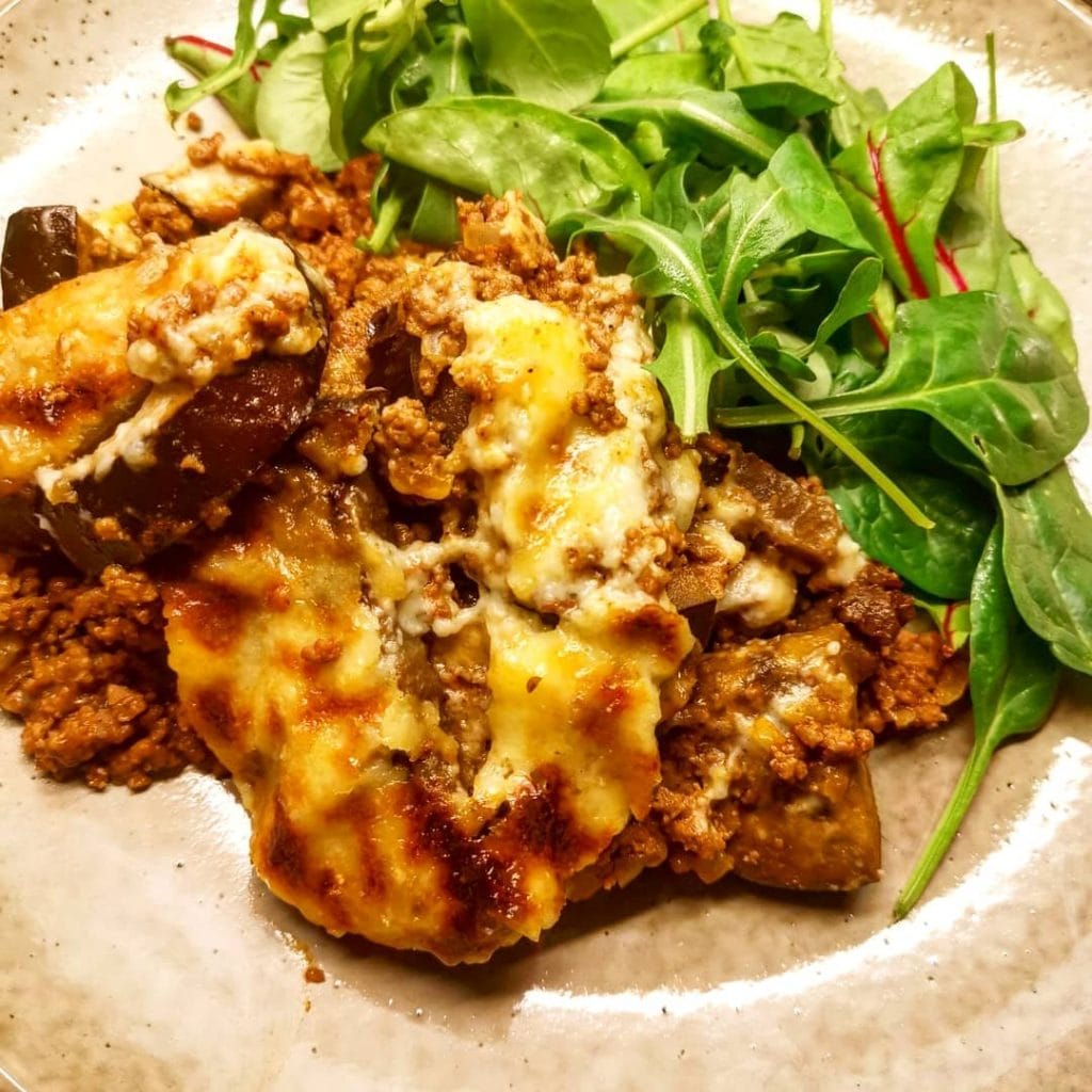 Enkel moussaka med gratinerad osttopp serverad med färsk ruccolasallad
