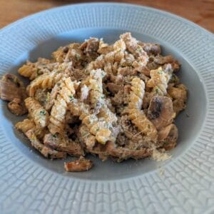 Krämig fläskfilépasta med champinjoner och färskost på blå tallrik