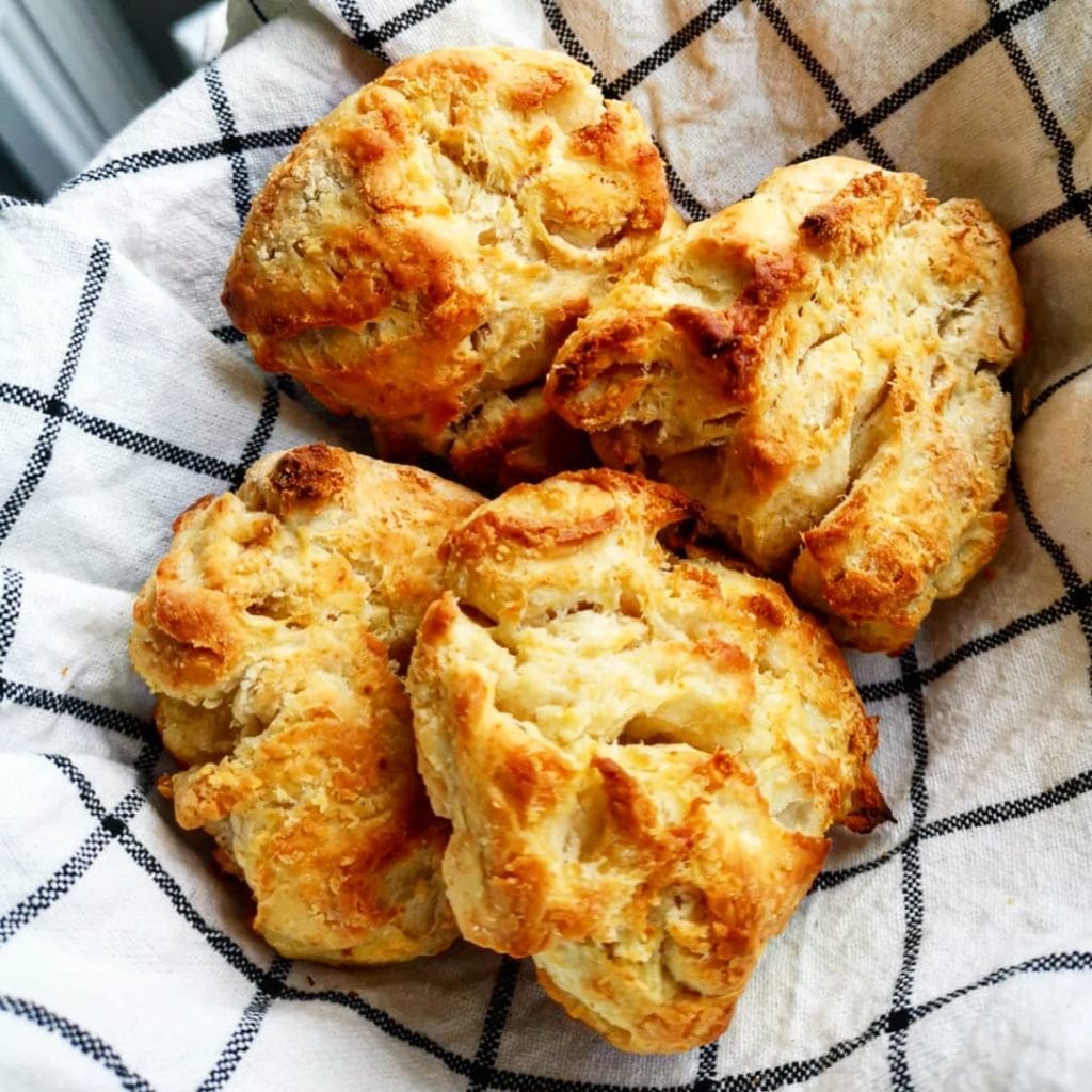 Klassiska scones nybakade på rutigt kökshandduk