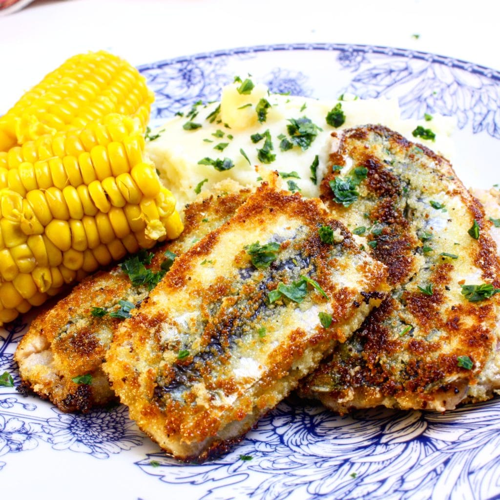 Stekt fylld strömming serverad med majskolv, kokt potatis och persilja