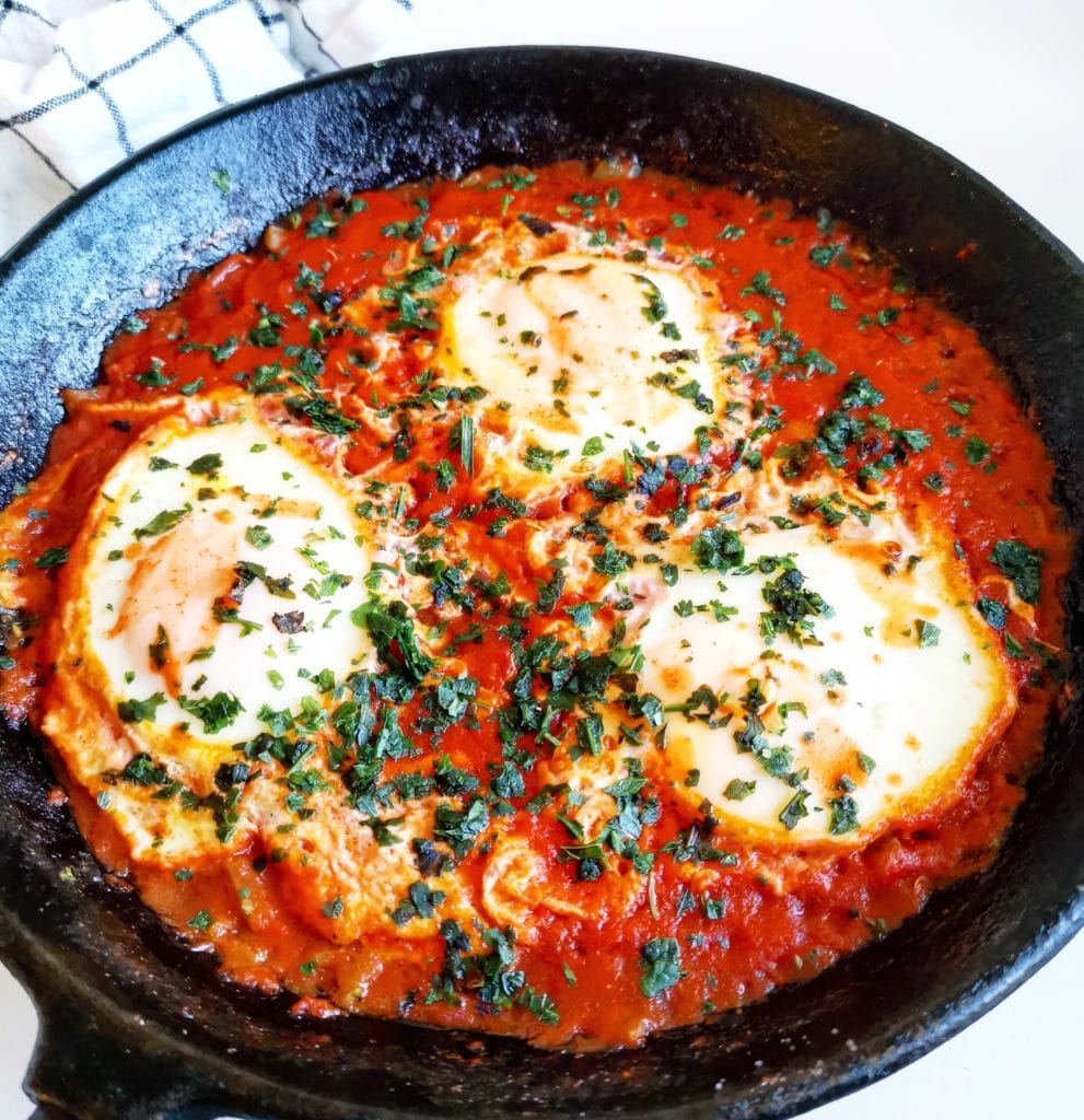 Enkel shakshuka med pocherade ägg i tomatsås toppad med persilja