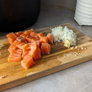 Krämig laxpasta skuren lax finhackad lök och vitlök på en skärbräda