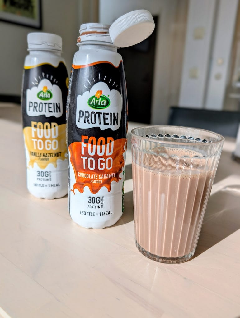 Arla Protein Food To Go upphälld i glas bredvid flaska