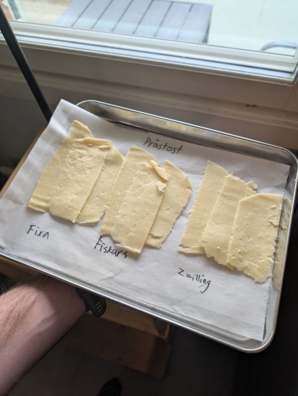 Bricka med tre högar ostskivor märkta Fixa, Fiskars, Zwilling